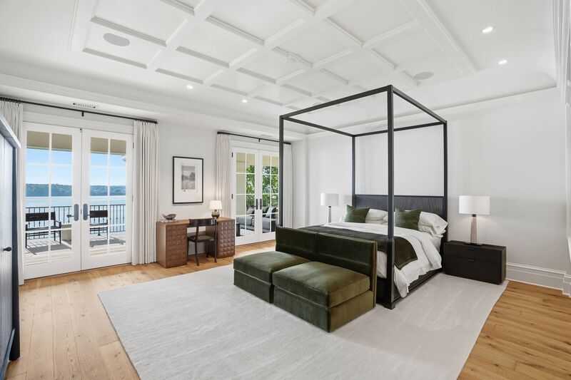 Primary bedroom suite with canopy bed and waterfront view